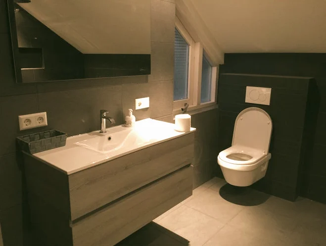 Badkamer met donker tegelwerk en een wastafelmeubel